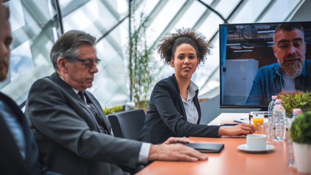 Manager e professionisti durante una riunione con collegamento video in contesto aziendale
